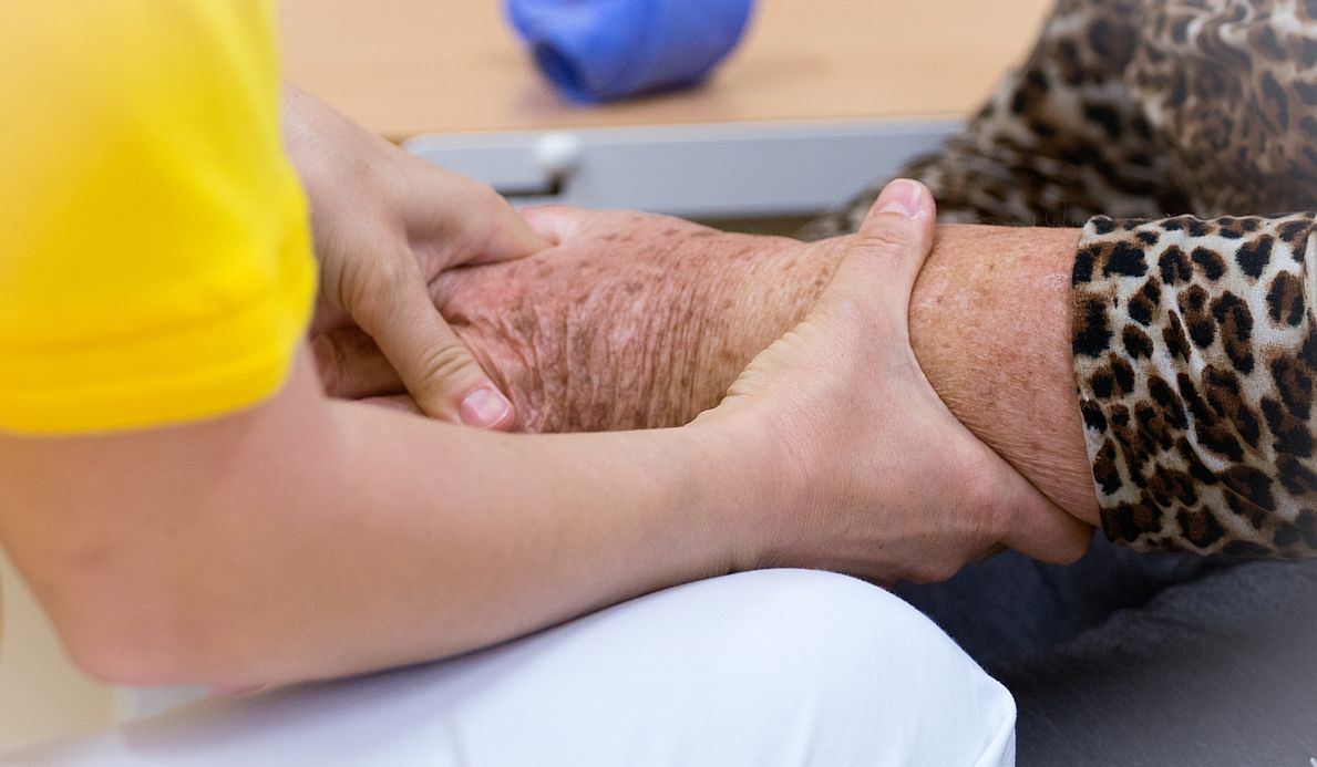 Betreuerin hält Hand einer Bewohnerin.