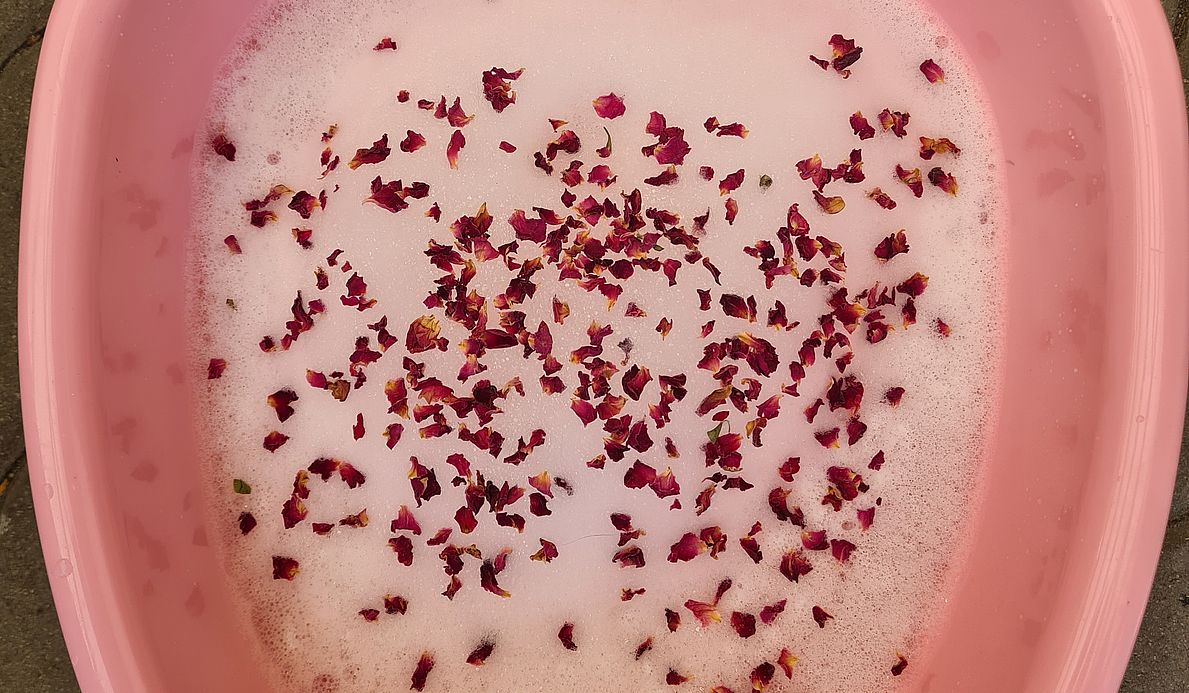 Eine Wanne, die mit Schaum und Blüten gefüllt ist.
